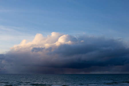 Dramatic dark blue gray yellow stormy cloudy sky and evening winter Baltic sea background photo.