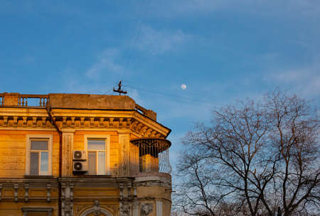 Odessa, Ukraine - 04 24 21: A part of yellow old building facade with windows, balcony and ancient...