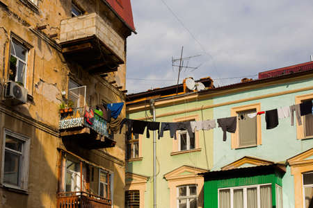 Odessa, Ukraine - 04 24 21: A part of the old building facade with windows and balcony. Typical houses in Odessa old town city center with linen and clothes drying on clothesline. Sunny spring photo.のeditorial素材