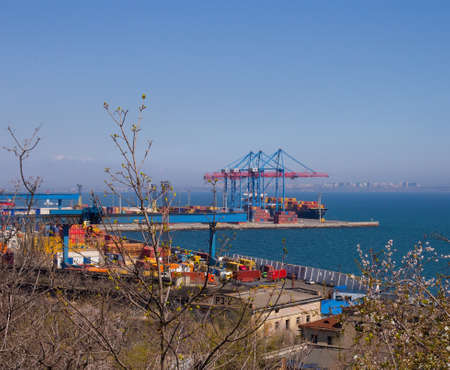 Odessa, Ukraine - 04 22 21: Containers, boats cranes and other industrial constructions in port docks. Bright sunny photo, looking through spring branches viewのeditorial素材