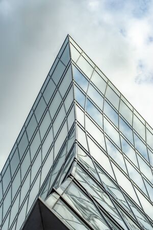 Abstract fragment of modern architecture, a wall of glass and concrete. Cloudy skyの写真素材