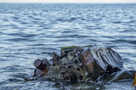 Old rusty engine lying among stones in the water.の写真素材