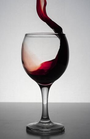 red wine splashing out of a glass, isolated on whiteの写真素材