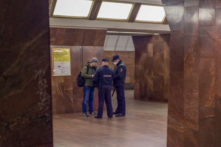 Moscow, Russia - April 17, 2020: Policeman checks the documents of citizen a platform in subway. Connection with COVID-19, access control effect.のeditorial素材