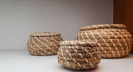 Decorative, colorful, wicker pots on the shelf. Three pots as interior decoration. Home comfort concept.の写真素材