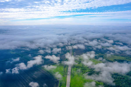 Road with cars, low clouds, shoot from a drone. Beautiful landscape from aboveの写真素材