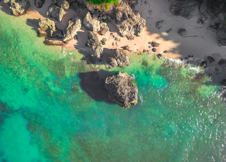 Stunning aerial view of Balis crystal-clear waters and rocky shoreline during summerの写真素材