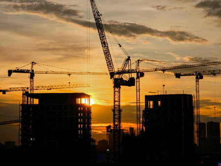 Construction site and tower cranes against the backdrop of a bright sunsetの写真素材