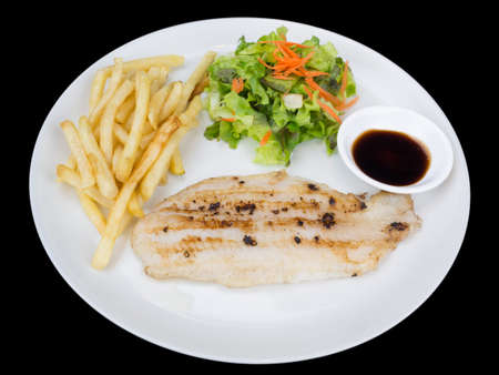 Fish fillet with french fries and salad isolated on the black background with clipping path