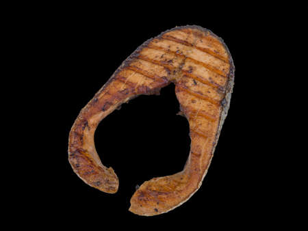 Salmon steak grilled isolated on the black backgroundの写真素材