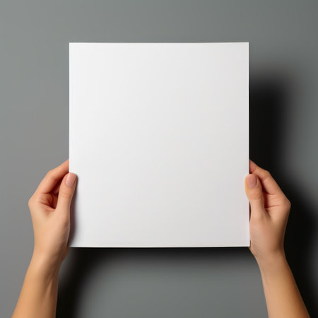 A woman's hand holding a blank paper on a grey background.の素材