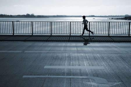 Female jogger passing a bridge. Motion blur.の写真素材