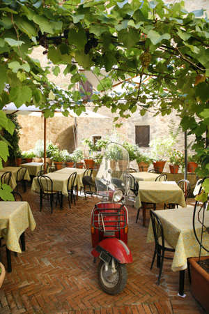 Old scooter parked in a closed restaurant - Pienza - Tuscany - Italy.の写真素材