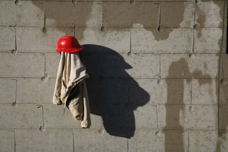 Construction worker taking a lunch break. Hard hat and jacket hanging on the wall making a nice shadow.の写真素材