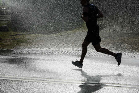 The runner passing a jet of water for cooling down the runners in the heat.の写真素材