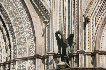 Detail of the facade of Orvieto Cathedral. (1290 - 1600 a. c.) Richly decorated with lots of stone mosaics and reliefs as well as pattern and artistic coils all over the facade. The eagel is a picture of the St John.の写真素材