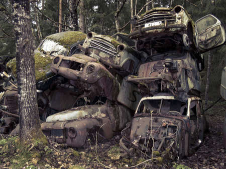 Heap of old cars left in the nature near the Norwegian border - Sweden.  From the series scrap in the wood. Cross processed.の写真素材