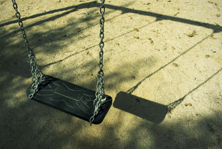 Deserted Croatian playground an early September morning. Focus on swing. Image is cross processed to reflect age.の写真素材