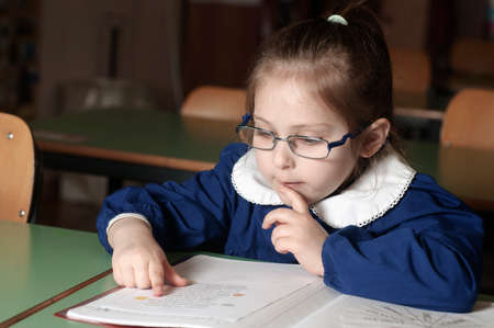 Italian elementary school girl (first-grader) reading on school desk. Educational and school conceptの写真素材