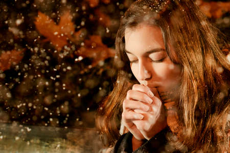 Caucasian girl warming herself in snowfallの写真素材