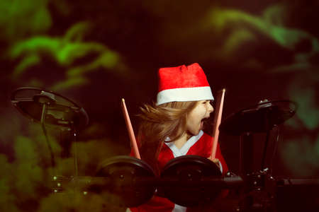 Little drummer disguised as Santa Claus playing the electronic drum kitの写真素材