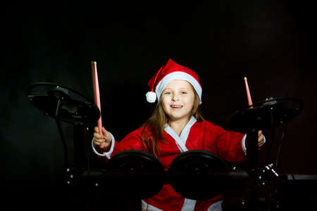 Little drummer disguised as Santa Claus playing the elettronic drum kitの写真素材