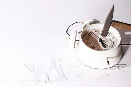 White crashed alarm clock, shards of glass and hammer on white background.の写真素材