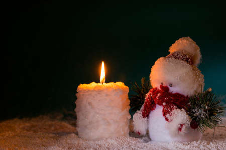 Snowman and burn candle on dark backgroundの写真素材