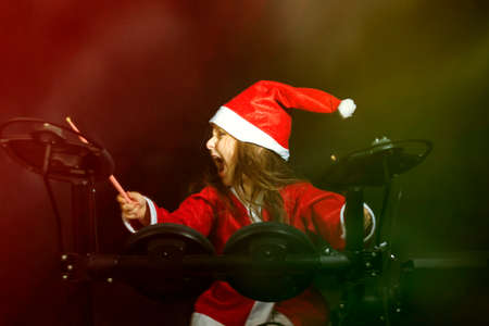 Little drummer disguised as Santa Claus playing the electronic drum kitの写真素材