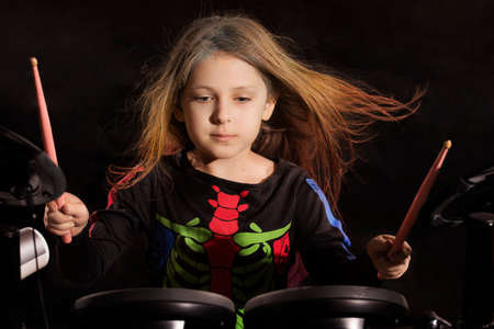 Little caucasian girl drummer with multicolored hair playing the electronic drum kitの写真素材