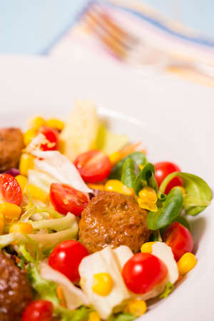 Colorful fresh vegetable salad with meatballs and corn seeds on rustic background. Copy spaceの写真素材