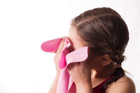 The face of little caucasian athlete after training, close-up portrait. Little girl wiping with a shammy, a chamois towel for diversportの写真素材