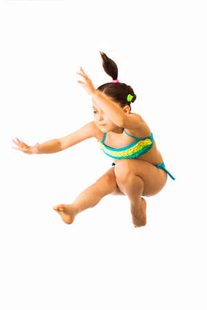 Little caucasian female 8 years old girl in multicoloured swimmwear jumping on white background.の写真素材