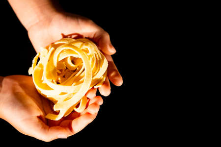 Hands of a little girl holding e fresh home-maded tagliatelle pastaの写真素材