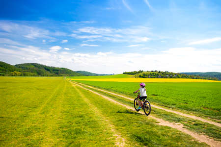 9 years girl going in bicycle across the fields in the sunny dayの写真素材