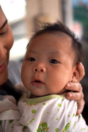 CHIANG MAI, THAILAND - February 19, 2014: A mather cradling her baby in her arms in Chiang mai, Thailand.のeditorial素材