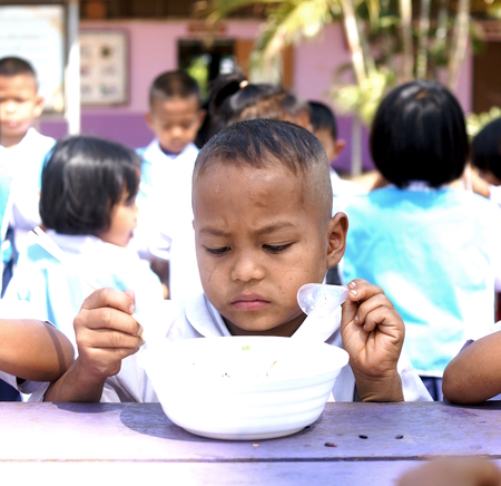 BAN BO NAM CHING, SA KAEW, THAILAND - February 10, 2014: Children eating, drinking and playing in the coutyard of a school in Ban bo nam ching, Sa kaew, Thailand.のeditorial素材