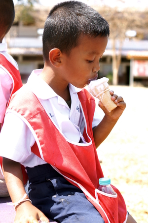 BAN BO NAM CHING, SA KAEW, THAILAND - February 10, 2014: Children eating, drinking and playing in the coutyard of a school in Ban bo nam ching, Sa kaew, Thailand.のeditorial素材