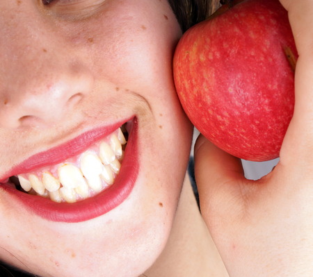Close up of the face of a young lady with red appleの写真素材