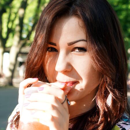 Young lady eating slush in the parkの写真素材