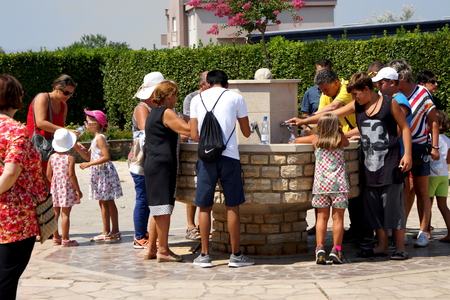 Medjugorje, Citluk, Bosnia and Herzegovina - August 12, 2015: Thirsty pilgrims take water from the fountain in front of the Church in Medjugorjeのeditorial素材