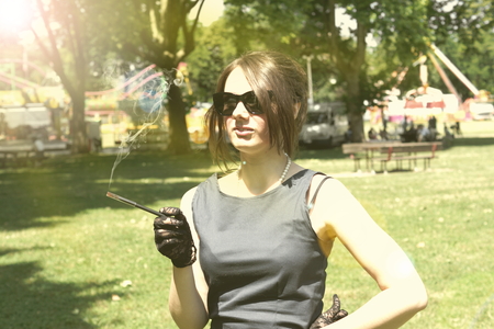 Picture of a smocking lady in the parkの写真素材