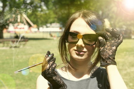 Picture of a smocking lady in the parkの写真素材
