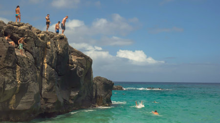 thrill seekers dive off the large rock at wiamea bayのeditorial素材