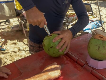 opening a green coconut to drink on copacabana beach, rio