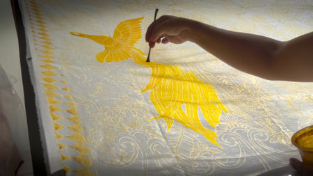 GIANYAR, INDONESIA - JUNE, 19, 2017: close up of an artist painting a yellow bird on batik fabric in baliのeditorial素材