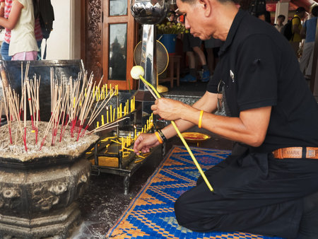 BANGKOK, THAILAND- JUNE, 21, 2017: thai man lighting a candle at wat pho temple in bangkokのeditorial素材