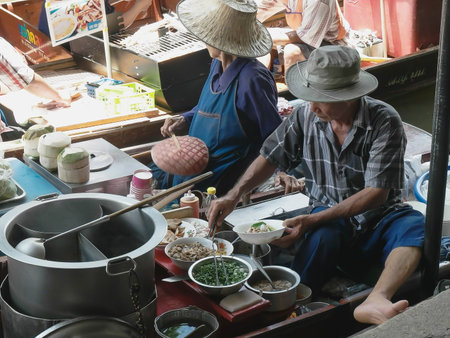 BANGKOK, THAILAND- JUNE, 23, 2017: a thai man cook serves food from a boat at damnoen saduak floating markeのeditorial素材