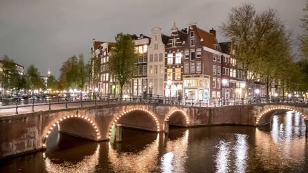 night view of canals, bridges and houses in amsterdamの写真素材