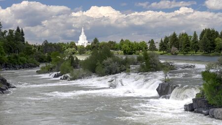 a waterfall and sunlit mormon temple at idaho falls in the united states of americaの写真素材
